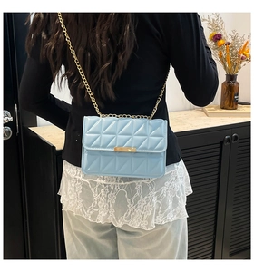 Detailed view of light blue quilted leather bag with golden chain and metal clasp