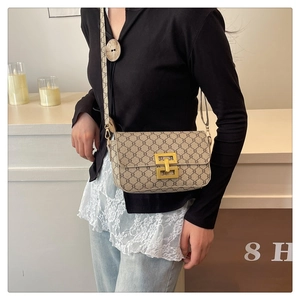Close-up of vintage printed crossbody bag with gold metal clasp on a female model
