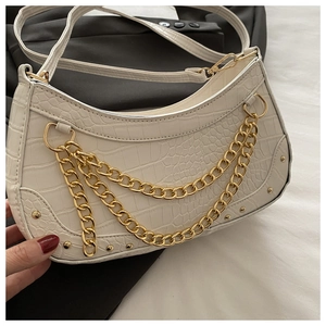 Detailed close-up of white crocodile pattern shoulder bag with triple gold chain straps