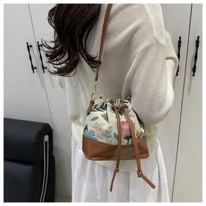 Mini floral canvas bucket bag shown on a model with drawstring leather details and strap