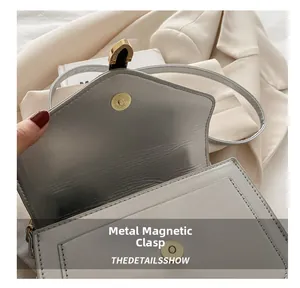 Detailed macro view of the golden magnetic snap and serpent head buckle on a white bag