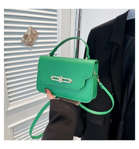 Detail of green faux leather handbag with golden bar metal lock and shoulder strap