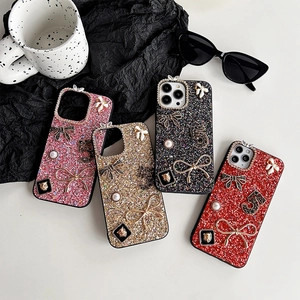 Glitter iPhone cases with pearls, metal bows and luxury charms on chic black background