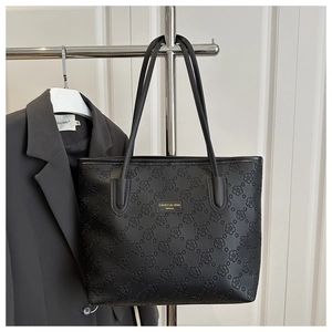 Detail view of black tote bag showing the delicate embossed floral texture and logo