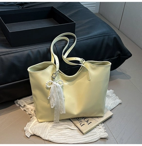 Dettaglio borsa tote grande color crema con fiocco in pizzo e perle su tessuto bianco