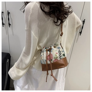 Close-up of floral embroidery detail on vintage drawstring bucket bag with leather base