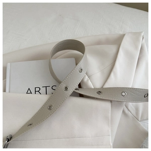 Detail of off-white leather strap with silver eyelets and fine stitching on a blazer