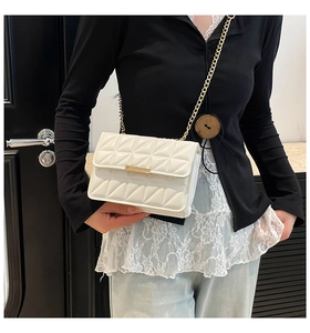 Detail of white quilted crossbody bag with golden chain and metallic buckle detail