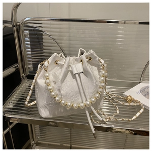 Close-up of white lace bucket bag featuring floral embroidery and pearl handle strap