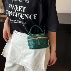 Deep green mini quilted crossbody bag with gold chain strap shown on a model