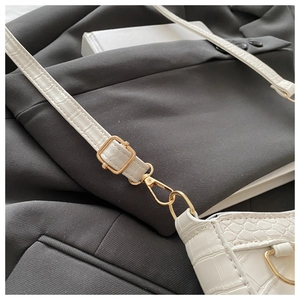 Detail of white crocodile embossed leather texture with golden metal hardware and strap
