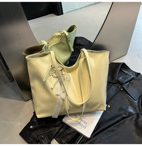 Dettaglio borsa tote giallo chiaro con ciondolo in pizzo e perle e finitura liscia