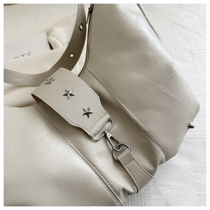 Detail of beige crescent bag showing lychee leather texture and silver star rivets