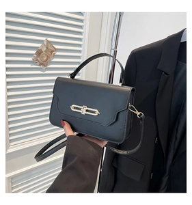 Close-up of black leather handbag featuring golden metal hardware and top handle strap