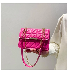 Close-up of rose red quilted crossbody bag with gold chain strap and metal lock