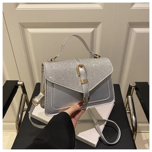 Detail of silver glitter flap and satin finish on a stylish square crossbody handbag