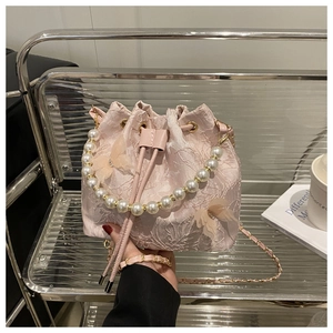 Detail of pink lace bucket bag with pearl handle and delicate butterfly accents
