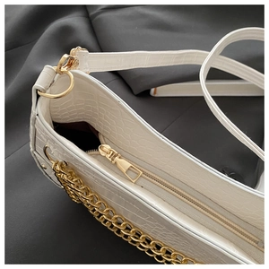 Detail of white crocodile embossed PU leather underarm bag with gold chain and zipper