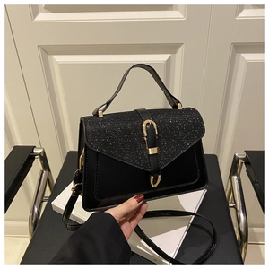 Detail of black structured crossbody bag featuring sparkling sequined flap and gold buckle