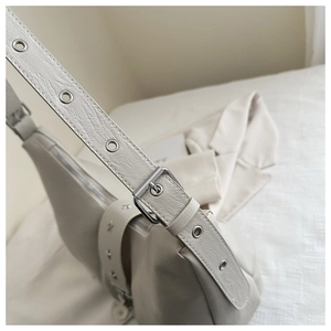 Detail of cream leather shoulder bag with silver eyelets and star rivet accents
