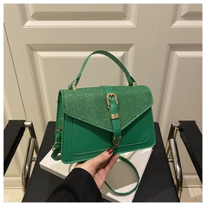 Close-up of green crossbody bag with textured glitter flap and gold buckle detail