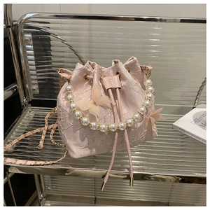 Detail of pink lace bucket bag featuring pearl handle and 3D mesh butterfly accents