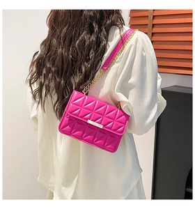 Detail of rose pink quilted crossbody bag with gold chain strap on a white shirt