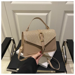Detail of beige shoulder bag with sparkling rhinestone flap and golden buckle closure