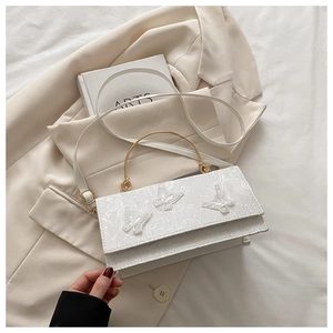 Detail of white lace handbag with butterfly embroidery and golden metal handle