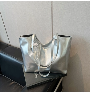 Detail of silver metallic tote bag featuring lace butterfly and pearl pendant ornament