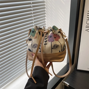Ethnic style bucket bag with floral jacquard and brown leather in a natural light setting
