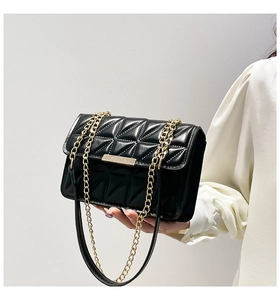 Close-up of quilted black crossbody bag featuring triangle stitching and gold chain