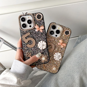 Macro detail of glitter iPhone case featuring rhinestone number five and butterfly charms