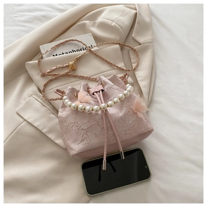 Detail of pink lace bucket bag with large pearl handle and woven metal chain strap