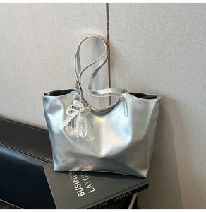 Borsa tote argento metallizzato con fiocco di pizzo bianco e perle su divano nero