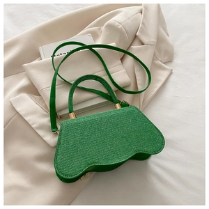 Détail du sac tissé vert avec fond ondulé, boucle dorée et fine bandoulière en cuir