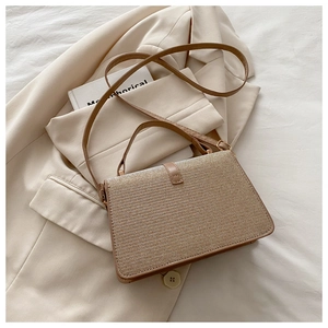 Close-up of woven texture on golden brown crossbody bag with top handle and strap