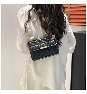 Quilted black leather crossbody bag with metallic clasp worn over the shoulder by a model
