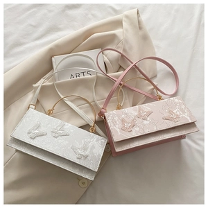 Close-up of white lace embroidery and 3D butterfly charms on small crossbody bags
