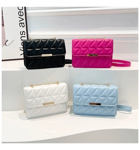 Close-up of quilted crossbody bags in four colors with gold metal chains on display