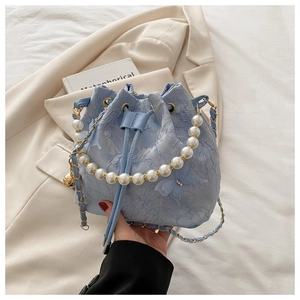 Detailed view of light blue lace bucket bag with pearl handle and butterfly pendant