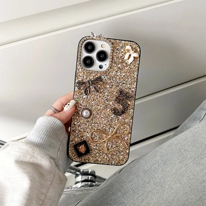Close-up of luxury iPhone case with champagne glitter, black bow, and pearl embellishments