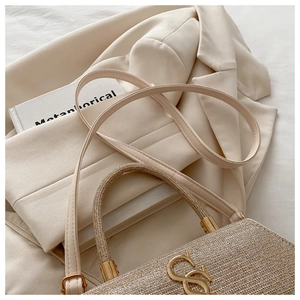 Détail du tissu pailleté champagne et du logo métallique en forme de S sur le sac à main