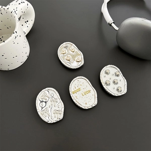 Minimalist silver phone grip set with gold heart, star and bow icons on gray desk