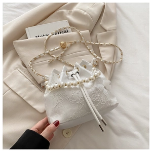 Detail of white bucket bag featuring floral embroidery, mesh petals, and pearl handle