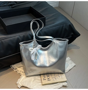 Dettaglio della borsa tote argento con fiocco in pizzo bianco e pendente di perle