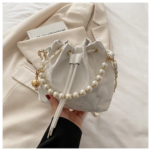 Detailed shot of white lace bucket bag with pearl handle and golden metal charm accents