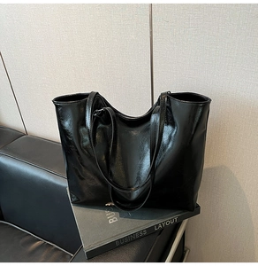 Dettaglio della borsa tote in pelle nera lucida con finitura a specchio e sottili tracolle