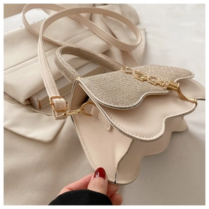 Gros plan détaillé du sac beige avec rabat pailleté doré et ornement métallique