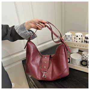 Detail of dark red hobo bag with star studs and soft matte texture shown by hand